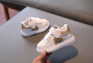 Detailed macro view of white toddler sneakers with cute plush bear patch and velcro strap