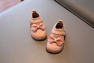 Détail de chaussures roses pour bébé avec nœud à carreaux et col en tricot