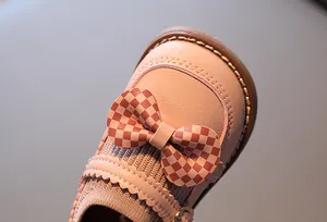 Détail d'une chaussure Mary Jane rose avec un nœud à damier et bord ondulé