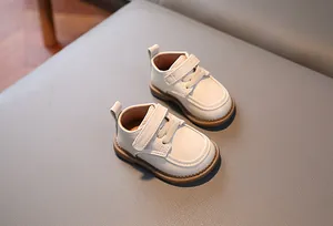 Dettaglio di mocassini per neonati bianco crema con velcro e suola in gomma marrone