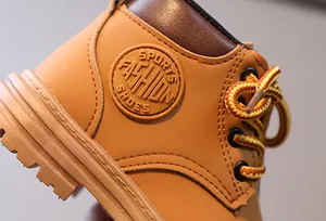Détail de bottines jaunes pour enfants montrant les coutures et l'étiquette sport