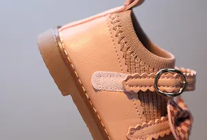 Détail de chaussures bébé roses avec nœud décoratif et bride velcro à bords ondulés