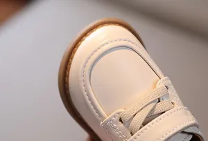 Dettaglio scarpe neonato in pelle crema con suola in gomma e cuciture a forma di U