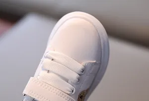 Detail of white leather kids sneakers showing neat stitching and velcro strap texture