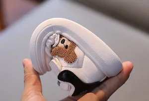 Close-up of flexible rubber sole on white toddler sneakers with brown bear embroidery