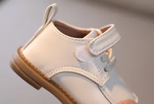 Dettaglio di scarpa morbida in pelle per neonati con velcro e suola in gomma antiscivolo