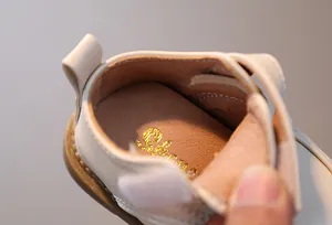 Dettaglio di mocassini per neonati in pelle beige morbida con suola interna imbottita