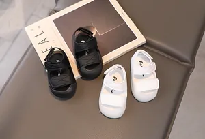 Detail of white and black toddler sandals with velcro straps and protective closed toes