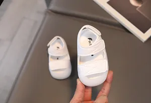 Detail of white infant summer sandals with dual hook-and-loop straps and soft soles
