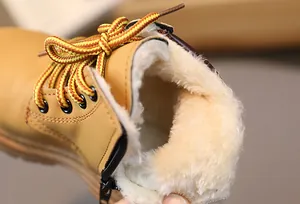 Detail view of winter kids boots showing thick white faux fur lining and side zipper