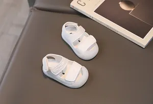 Detail of white baby sandals featuring secure dual velcro straps and protective closed toe