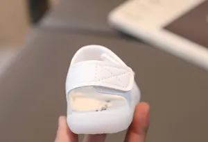 Detailed view of white baby sandal heel with reinforced stitching and velcro strap closure