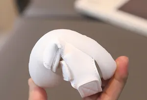 Macro shot showing the ultra-flexible soft sole of white baby sandals being bent by hand