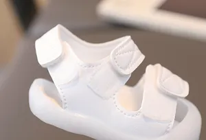 Close-up of white baby sandals featuring quilted PU leather and triple velcro straps