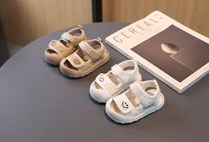Dettaglio dei sandali per neonati beige e bianchi con ricamo smiley e velcro