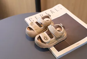 Dettaglio di sandali beige per neonati con doppia chiusura a strappo e ricamo a faccina