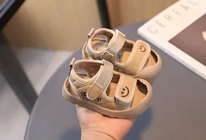 Dettaglio dei sandali per neonati kaki in ecopelle trapuntata con ricamo di una faccina