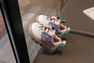 Detail view of children's sneakers with color-block design and quick-adjust toggle lace