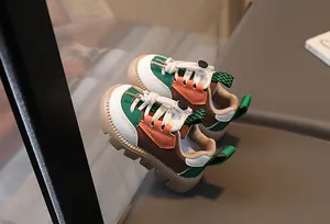 Detail of color-block kids sneakers featuring brown and green panels with toggle laces