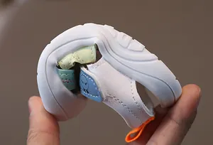 Detailed view of flexible rubber sole on white baby sandals showing soft non-slip grip