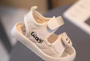 Dettaglio dei sandali per neonati bianco avorio con texture trapuntata e ricamo Lucky