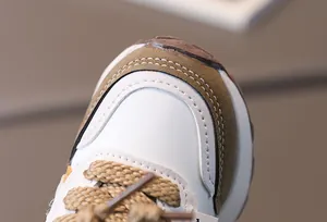 Detail of kids athletic shoes with premium white leather and brown suede stitching