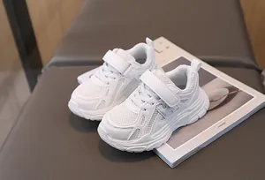 Close-up of white breathable mesh kids sneakers with velcro straps and anti-slip soles