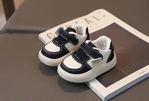 Détail de baskets pour bébé avec empiècements en cuir noir et blanc et velcro