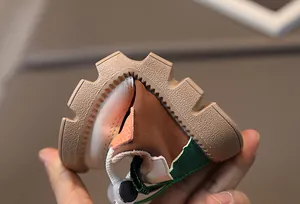 Close-up of flexible non-slip rubber sole on kids patchwork sneakers showing soft elasticity