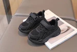 Detail view of breathable black mesh sneakers for kids with Velcro strap and thick sole