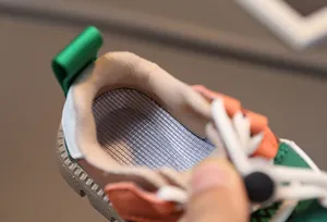 Detail of breathable striped mesh insole and adjustable toggle on kids sports shoes