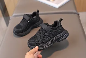 Detail of black breathable mesh kids sneakers with Velcro strap and cushioned mid-sole