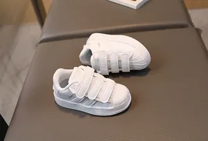 Detail of kids shell-toe white sneakers with triple hook-and-loop straps and texture