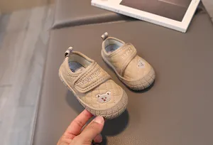 Detail of toddler soft-sole shoes with quilted fabric, rubber toe cap, and bear embroidery