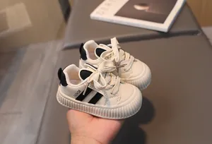 Detailed macro view of cream toddler shoes featuring anti-slip soles and fashion stripes