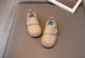 Close-up of beige toddler shoes with soft soles, cute bear patch, and velcro straps