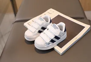 Detail shot of kids white shell-toe sneakers with triple navy straps and velcro closure