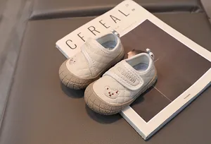 Detail of toddler cream shoes with diamond quilting and brown bear embroidery motif