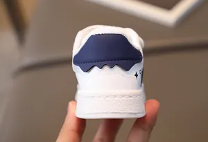 Detail of children's white leather sneakers with blue heel accent and non-slip textured sole