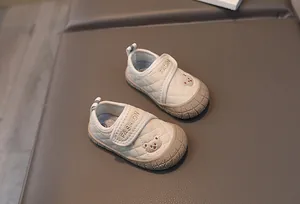Detail of baby walking shoes with quilted fabric, bear embroidery, and Velcro closure