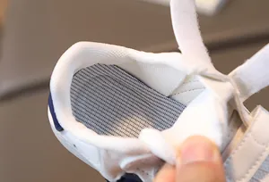 Detailed interior of kids shell-toe sneaker showing breathable mesh lining and velcro strap