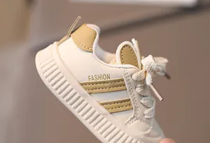 Close-up of baby walking shoes showing cream and khaki panels with fashion lettering