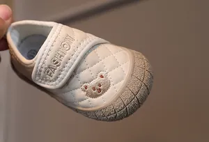 Detailed shot of cream toddler shoes with quilted stitching and embroidered bear motif