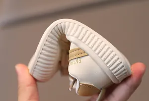 Detail shot of baby shoes showing the flexible and soft rubber sole being bent easily