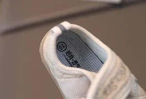 Detail view of toddler walking shoe featuring quilted beige fabric and soft padded insole