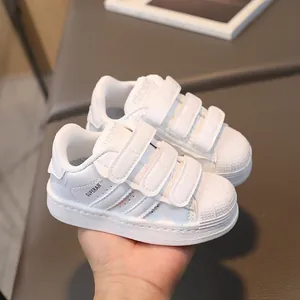 Classic white kids shell toe sneakers with triple velcro straps and side stripes