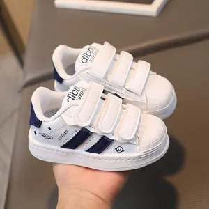 White shell-toe kids' sneakers with navy stripes and three hook-and-loop straps