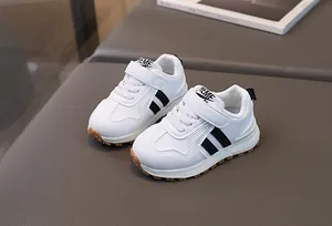 Detail of white toddler sneakers with black stripes and secure velcro closure straps