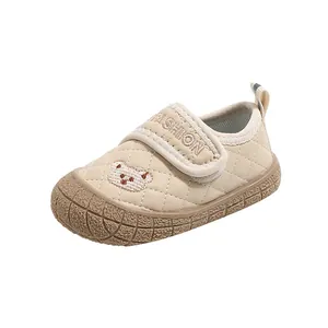 Beige infant shoes with quilted pattern, bear embroidery, and non-slip rubber soles