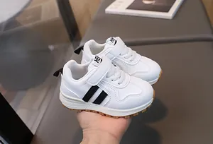 Detail of white leather baby sneaker with black stripes and non-slip gum rubber sole